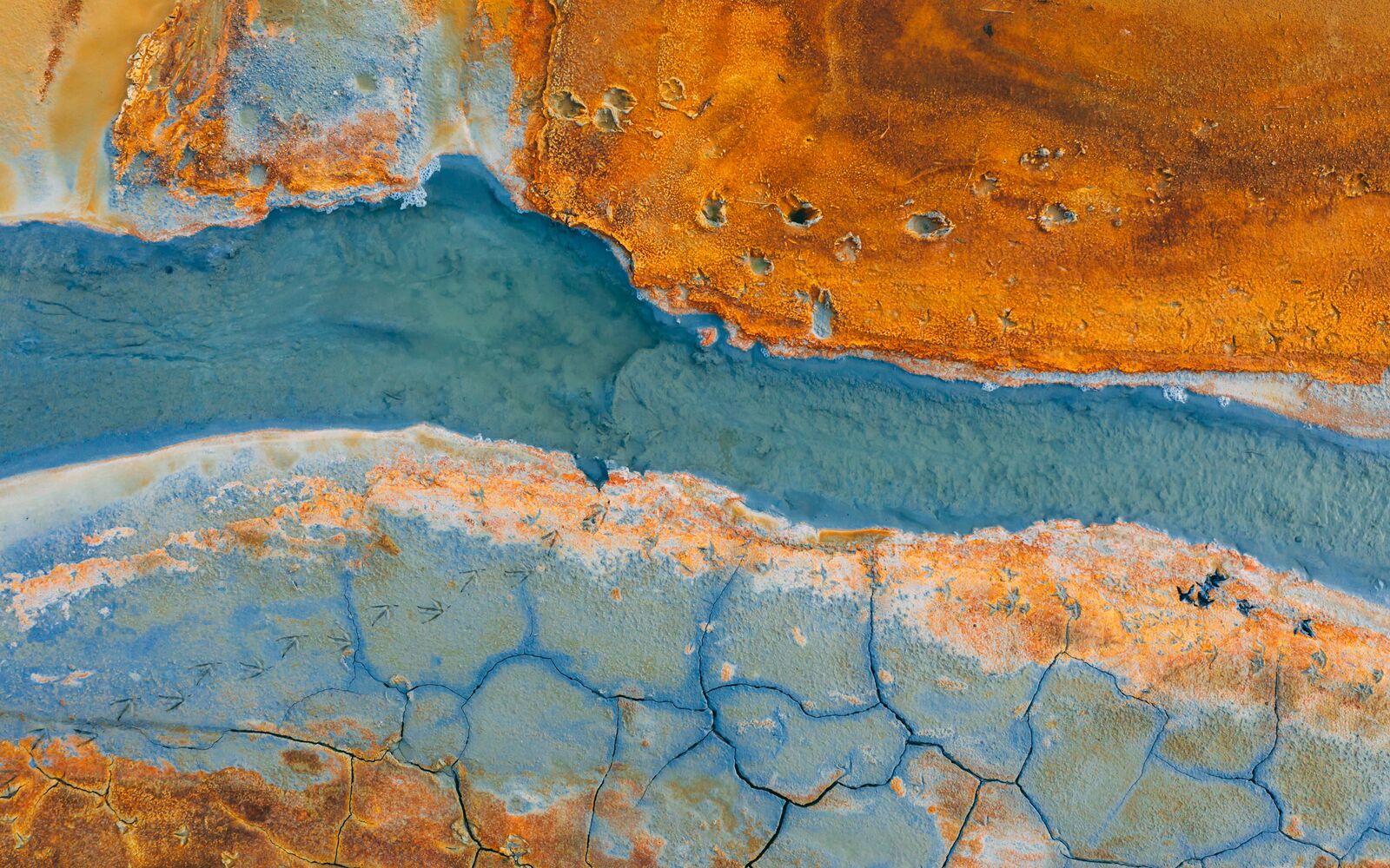 Top down aerial view from drone on geothermal icelandic in Iceland Seltun  Krysuvik Kleifarvant lake blue water and orange ground texture structure hot spring mud background foot prints animals birds; Shutterstock ID 1447441286; purchase_order: Main Visual; job: ; client: ; other: